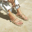 Person wearing rope sandals on a light stone pavement
