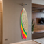 Decorative rope surfboard with red, yellow, and green stripes on a wall in a modern room.