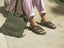 Person wearing green rope sandals and holding a green rope bag on a concrete surface.