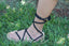 Romano sandal with black rope straps on a grassy background